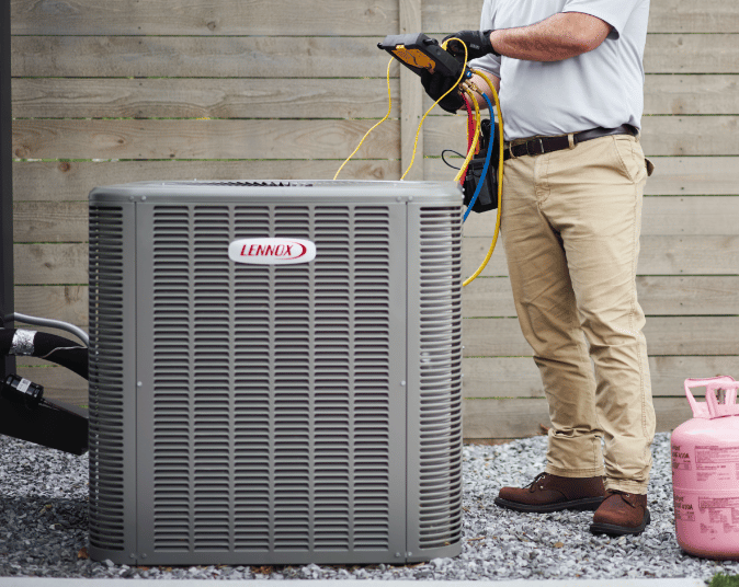 A HVAC technician works on a Lennox air conditioner.