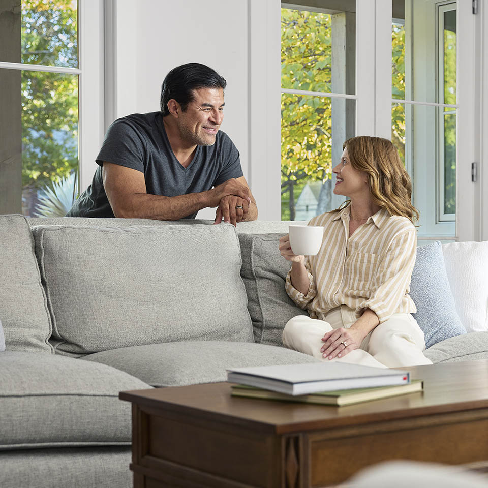 A man and a woman in a living room, smiling and interacting.
