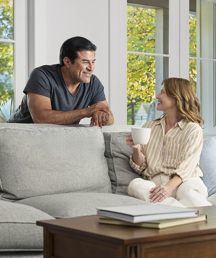 A man and a woman in a living room, smiling and interacting.